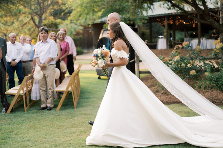 bride and father approach wedding pergola