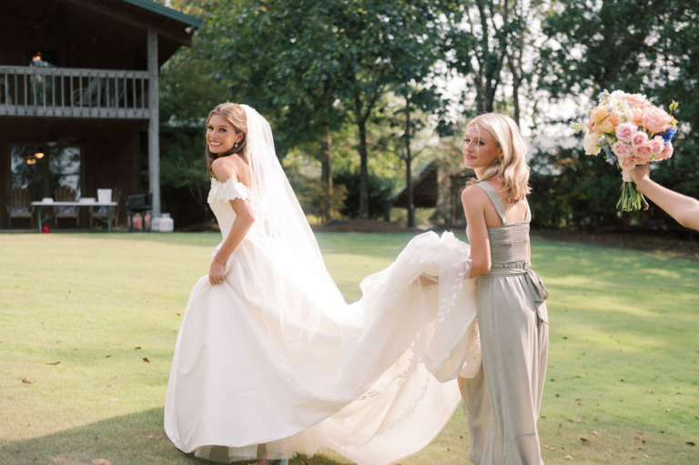 bride and attendee holding dress on lawn